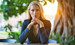 Vanessa Kerry seated, elbows on table, hands clasped in front of chin, behind her sun sets behind a large tree, in Lusaka, Zambia.