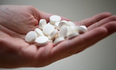 A person's hand holding white pills