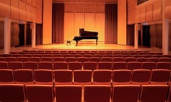 image of a piano on stage inside an empty concert hall<br>GettyImages-1225580980