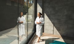 A woman in a white bathrobe enjoying a luxury spa with a swimming pool