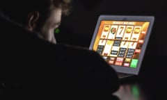 Pic of a man in a darkened room looking at an online slot machine on a laptop