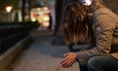 Young woman sitting on a bench looking down at night<br>Unhappy blonde girl sitting on a bench in the street at night looking down with hair covering her face. Focus on the foreground with bokeh of streetlights in the background. Vitoria-Gasteiz, Alava province, Basque Country, Spain, Europe.