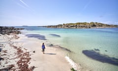 A high angle view of an independent young woman walking on the white sand with the crystal clear blue waters of Iona, Scotland<br>On the western coast in the Inner Hebrides A high angle view of an independent young woman dancing on the white sand with the crystal clear blue waters of Iona, Scotland - stock photo On the western coast in the Inner Hebrides