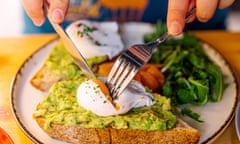 A breakfast plate with brown toast, poached eggs, avocado and spinach.