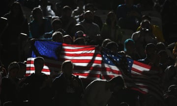 Supporters hold a US flag during the women’s beach volleyball qualifying match between the USA and Switzerland.