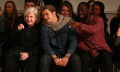 Patsy Rodenburg, pointing, sits in a chair next to former students Orlando Bloom, with a wool scarf around his neck, and Paapa Essiedu, in a shirt and also pointing, all of them smiling