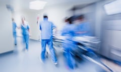 Blurred photograph of hospital staff pulling a trolley