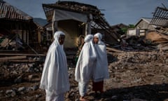 Indonesian women stand before damaged houses in Pemenang, Lombok