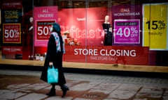 Pedestrians walk past the window display of a Debenhams shop on Oxford Street in central London, with "store closing" signs