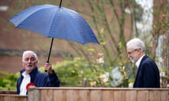 Man leans open umbrella towards Jeremy Corbyn