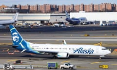 a white and blue airplane on a runway with planes and buildings in the background