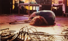 Cobain in the spotlight, lying limply on stage clutching his guitar