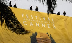 Workers set up a banner of the official poster of the Cannes Film Festival