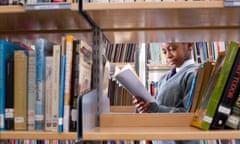 Student in school uniform looks at a book in a library