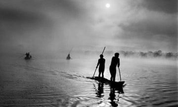 People punt small boats across a body of water.