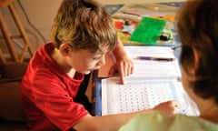 A boy sits at a table at home with workbooks in front of him