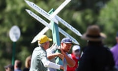 Bryson DeChambeau of the United States moves a sign while preparing to play his second shot on the 13th hole from the 14th fairway.