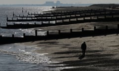 A man walks along the beach on the Suffolk coast with the Sizewell B nuclear power station seen on the horizon.