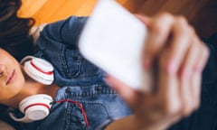 Woman taking selfie while lying on the floor