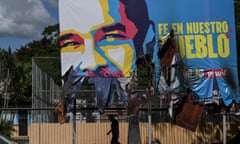 A man walks under a giant billboard with the vandalized image of Venezuelan president Nicolas Maduro