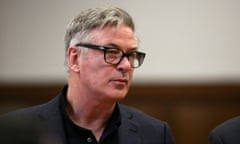 Middle-aged white man with black-framed glasses appears to stand and listen closely inside a courtroom.