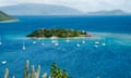 Verdant island surrounded by sailing boats.