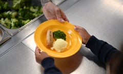 A school chef serves cooked hot food to students on their lunch break at St Luke's Church of England Primary School in East London.