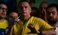 Jair Bolsonaro in yellow with a microphone surrounded by supporters
