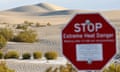 a red sign that says stop extreme heat danger in front of sand dunes