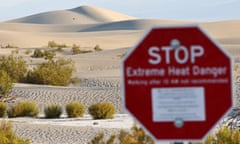 a red sign that says stop extreme heat danger in front of sand dunes