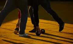 Two people play crown green bowls