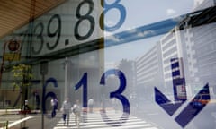 People are reflected on an electronic board showing Japan's Nikkei average outside a brokerage at a business district in Tokyo