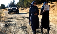 Palestinian teenagers walk to school accompanied by Israeli soldiers in a jeep to prevent attacks on them by Jewish settlers.