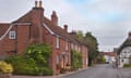 A street in Broughton with a red brick terrace of houses on the left and a thatched cottage on the right