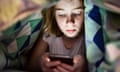 Girl lying under a cover in bed looking at her smartphone