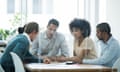 Five people in business clothes sit around a table