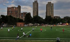 Young men play soccer as mothers and fathers socialize and parent their playing children in Currie Park