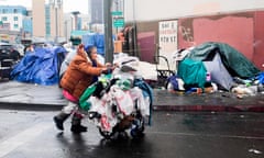 A homeless woman pushes her belongings past a row of tents on the streets of Los Angeles, California.