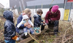Two women and three children in coats, hats and gloves in the community garden.