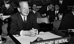Dag Hammarskjöld sitting at a desk with a plaque in front of him reading 'secretary general'.