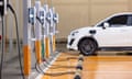 An electric car parked up and plugged in at a row of charging sockets