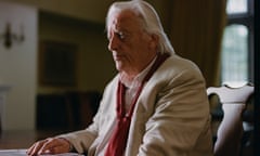 Michael Mansfield KC, in a shirt, cardigan and jacket and long white hair, his hand on a table, looks serious