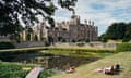 A shot from Saltburn featuring an angular view of Drayton House with characters sunbathing on the grass in the foreground.