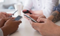 Close up of friends texting with cell phones at table