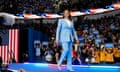 woman wearing light blue suit stands on stage and looks up at crowd