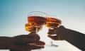 A close-up shot of friends clinking sparkling wine glasses at sunset. Refreshing cocktail drinks. Summer outdoor parties and celebrations concepts