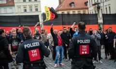 Police facing protesters waving flag