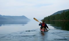 Haida Gwaii, Canada. Guide Gord Pincock leads an early morning paddle on the calm waters in Gwaii Haanas