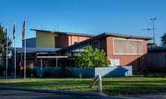 View of entrance to institutional-looking building with flagposts out the front