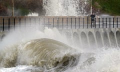 A man takes a picture of waves crashing on the promenade as Storm Franklin whips up strong winds in Folkestone, Kent, in February.